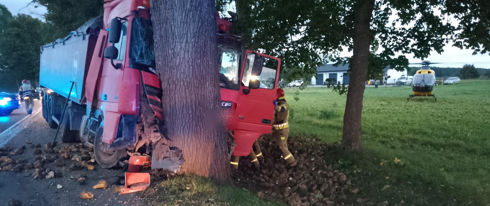 Zdjęcie przedstawia uszkodzony pojazd ciężarowy po uderzeniu w drzewo