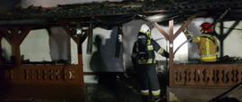 Spalony dom przed domem stoją strażacy i dogaszają pożar