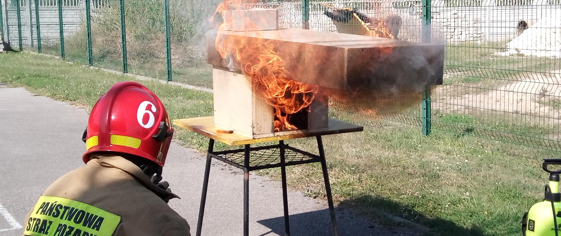 Strażak pokazuje proces palenia małego domku do szkolenia
