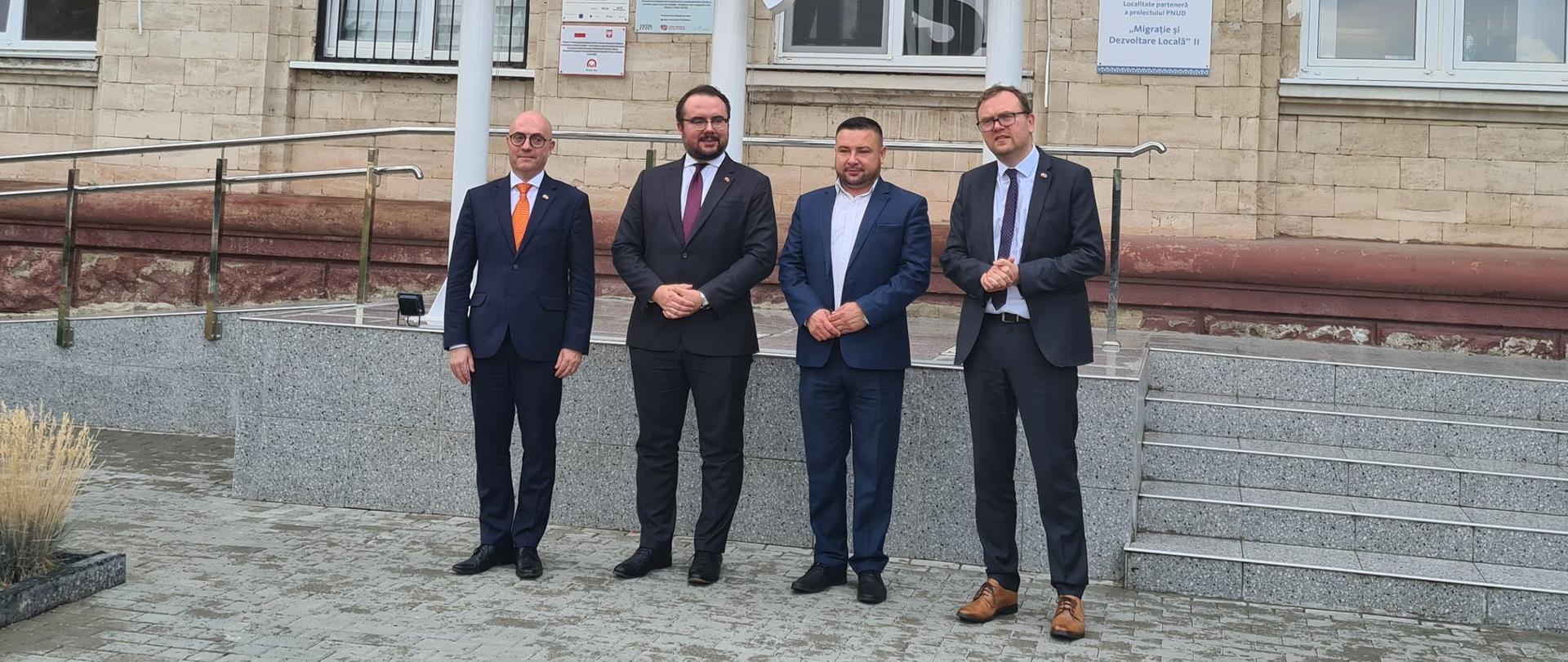Czterej mężczyźni w garniturach na tle urzędu miasta w Mołdawii.