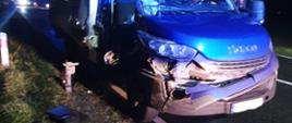 Uszkodzony samochód dostawczy stoi na poboczu drogi.