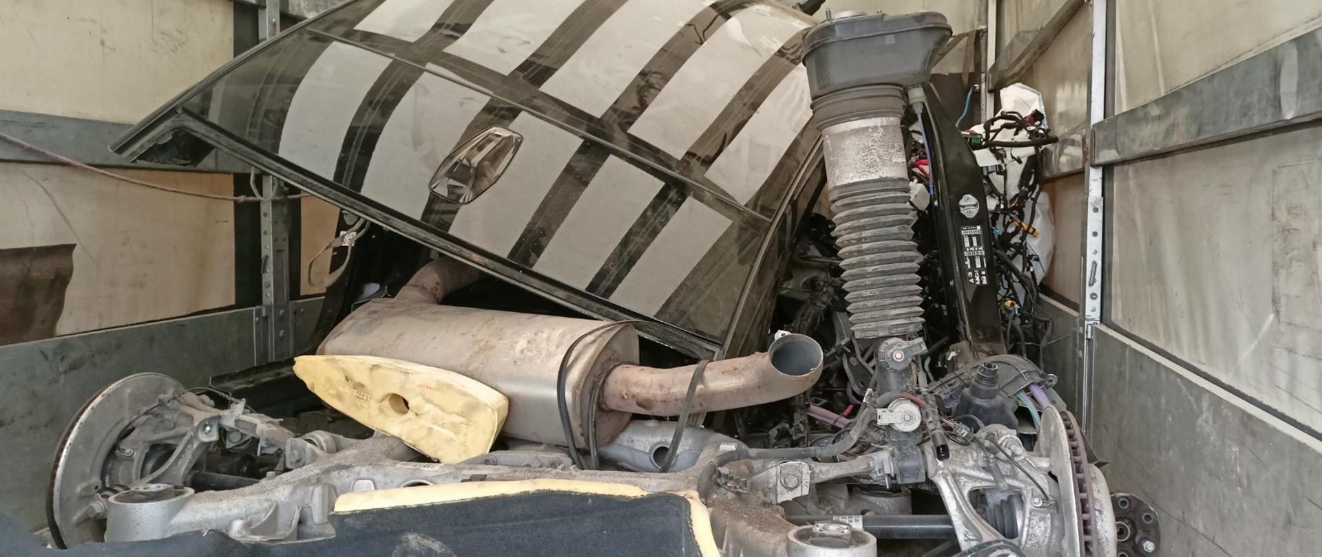 We wnętrzu ciężarówki ułożone w stos zużyte różne części samochodowe.