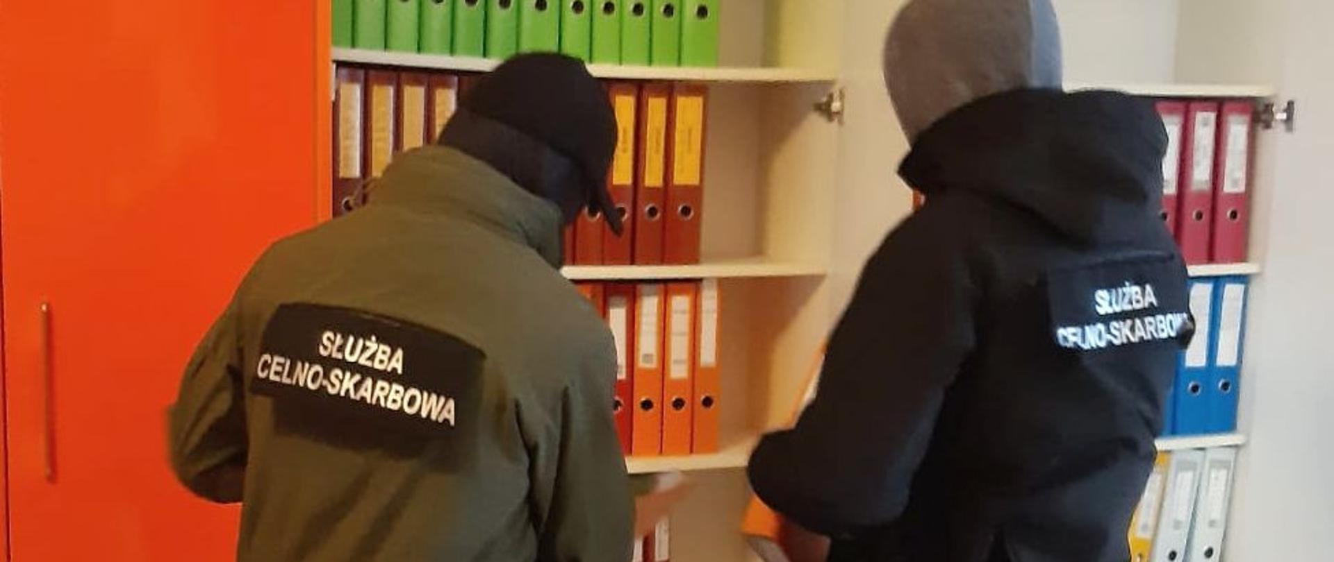Funkcjonariusze Służby Celno-Skarbowej przy szafie z dokumentacją księgową.