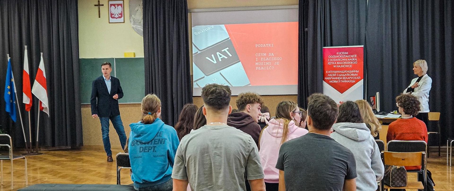 Edukatorzy Akademii Podatkowej Podlaskiej KAS prowadzą lekcję w II LO z Dodatkową Nauką Języka Białoruskiego w Hajnówce, prezentacja na rzutniku: podatki, czym są i dlaczego musimy je płacić
