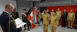 Komendant Powiatowy czyta rotę ślubowania, po środku sztandar komendy oraz nowi funkcjonariusze.
