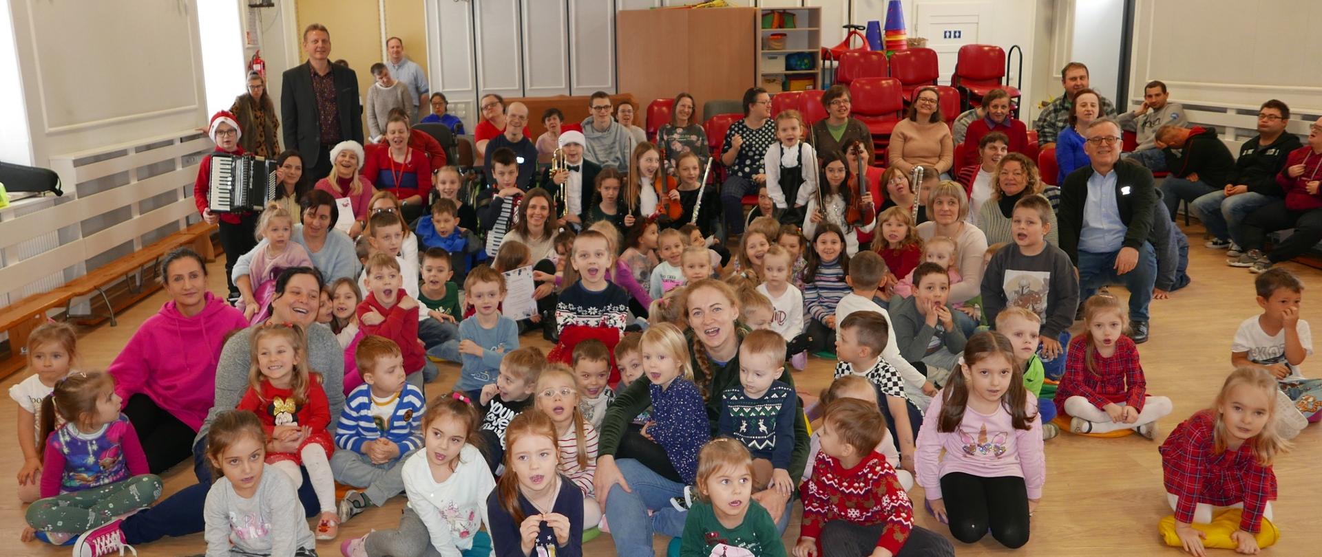Zdjęcie grupowe przedszkolaków, uczniów szkoły muzycznej, nauczycieli i uczestnikami Terapii zajęciowej Caritas