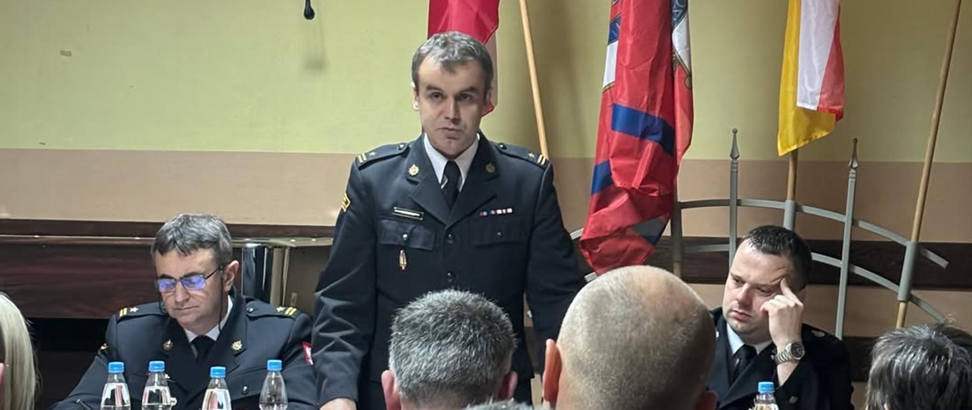 Na zdjęciu widać druhów Jędrzejowice w mundurach strażackich siedzących przy stole w remizie OSP Jędrzejowice. Przy stole siedzą również p.o. Komendant Powiatowy PSP w Ostrowcu Św, 