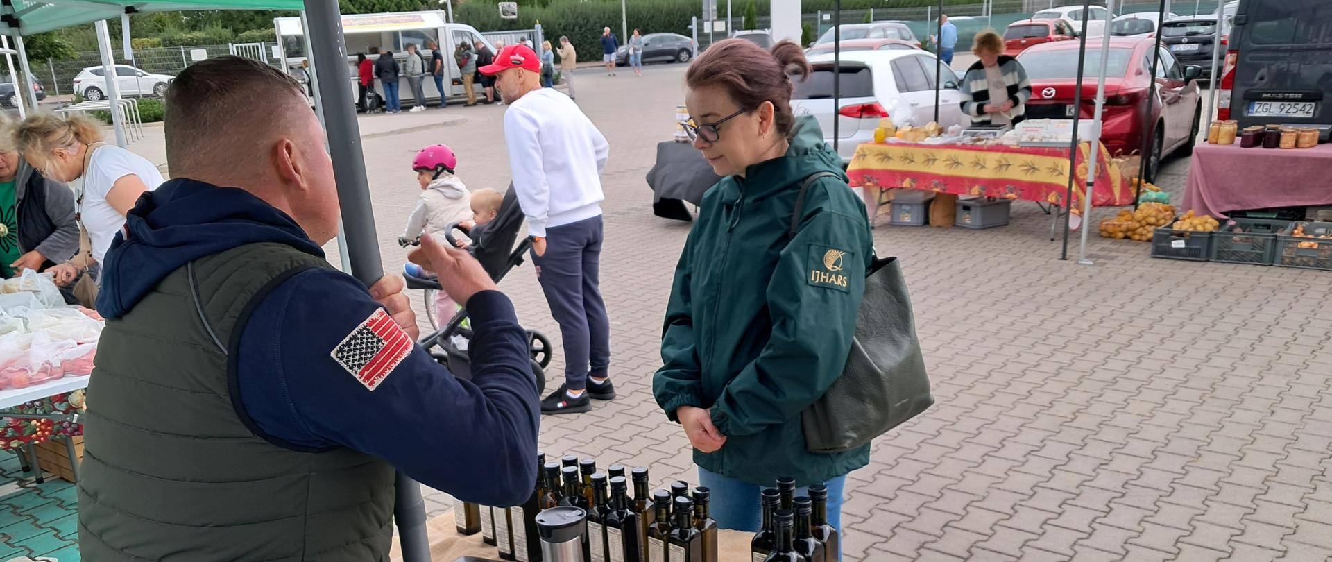 Inspektor IJHARS na stoisku z miodami podczas rozmowy ze sprzedającym