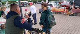 Inspektor IJHARS na stoisku z miodami podczas rozmowy ze sprzedającym.