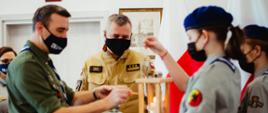 Przedstawiciele harcerzy w obecności pomorskiego komendanta wojewódzkiego Państwowej Straży Pożarnej zapalają Betlejemskie Światełko Pokoju.