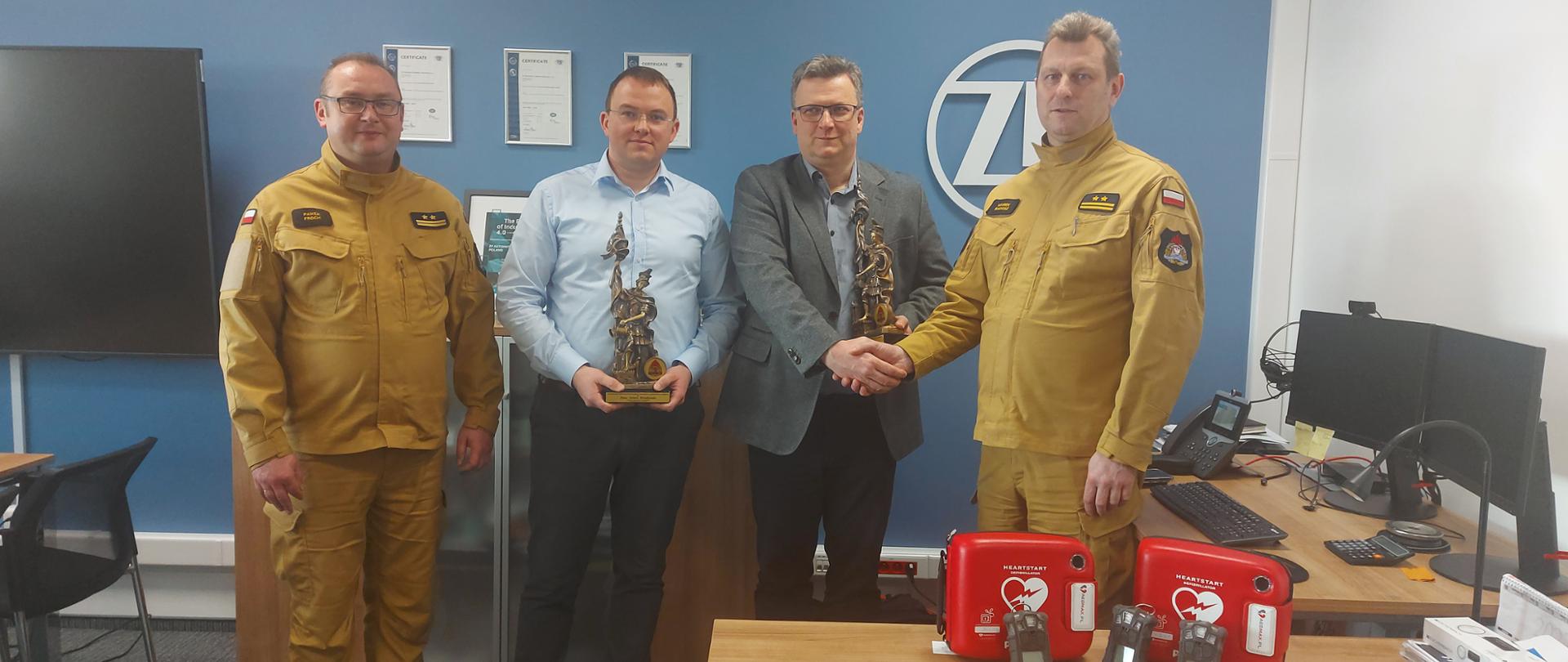 Na zdjęciu Komendant Miejski Państwowej Straży Pożarnej w Częstochowie wraz z Zastępcą oraz Dyrektor Zakładu Elektroniki ZF Automotive Panem Krzysztofem Gablankowskim i Dyrektorem ds. Infrastruktury i Utrzymania Ruchu Zakładu Elektroniki ZF Automotive Panem Arturem Dziadynakiem podczas przekazania sprzętu dla Komendy Miejskiej Państwowej Straży Pożarnej w Częstochowie.
