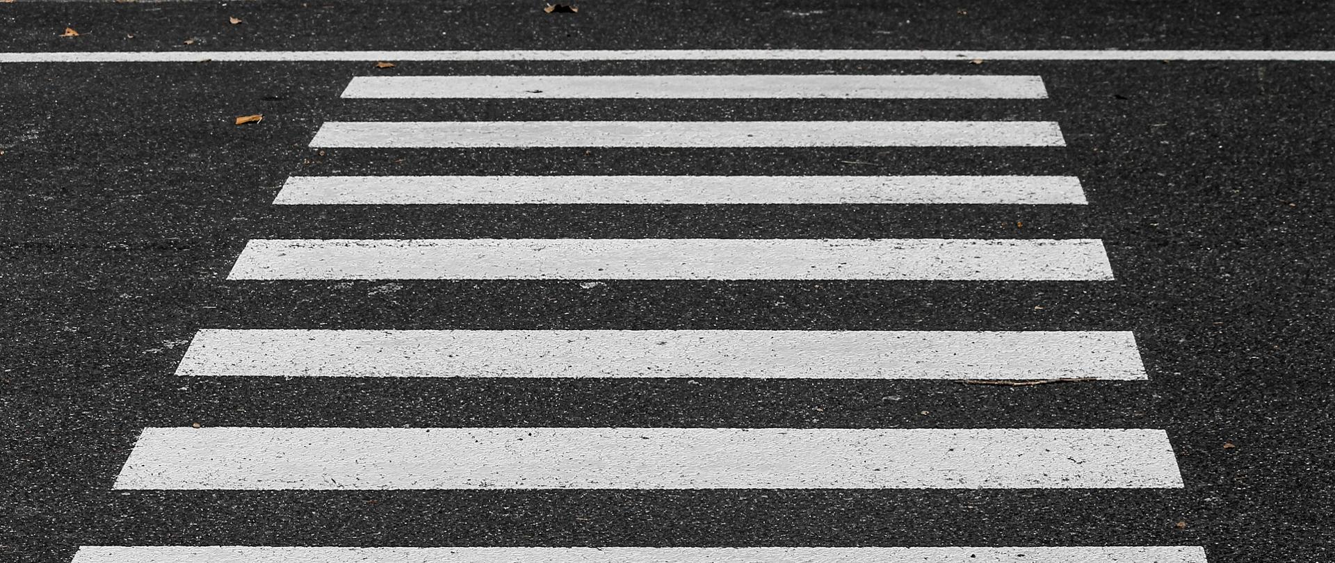 Na zdjęciu fragment asfaltu, na którym narysowane są pasy - zebra, przejście dla pieszych. 
