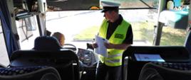 Funkcjonariusz mazowieckiej Inspekcji Transportu Drogowego pobiera wymagane dokumenty od kierowcy autokaru i przygotowuje się do pobrania danych cyfrowych z pamięci tachografu.