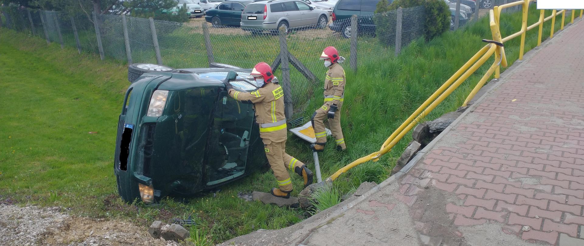 Strażacy zabezpieczają samochód przewrócony na lewy bok