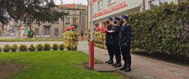 Poczet flagowy ze złożoną flagą stoi przed masztem flagowym