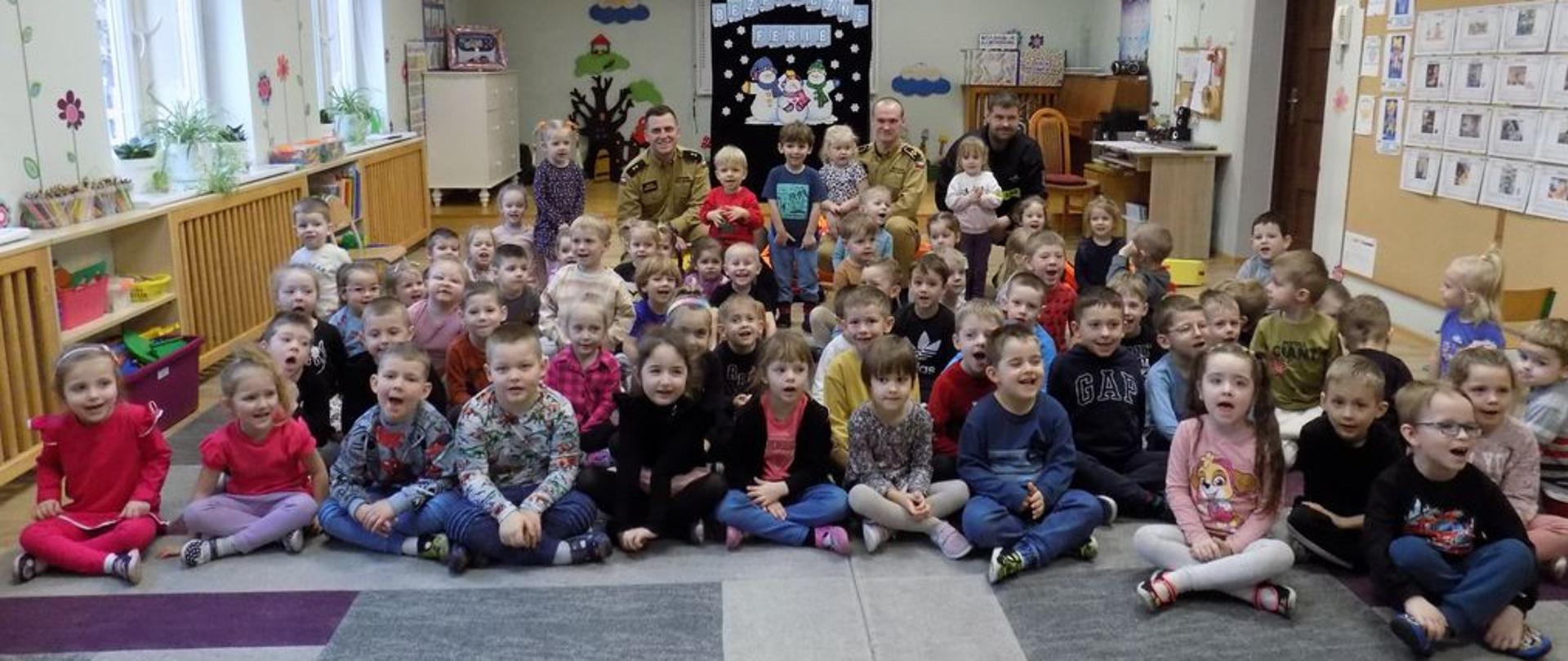 Grupa dzieci podczas zajęć w przedszkolu ze strażakami