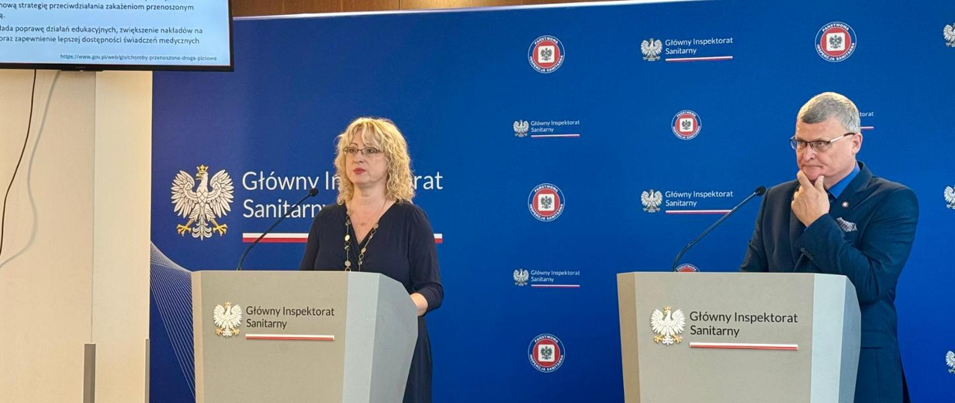 Briefing dotyczący kampanii informacyjnej "Bezpieczne wakacje z sanepidem". Po lewej stronie prof. Justyna Kowalska, ekspertka GIS. Po prawej stronie dr n. med. Paweł Grzesiowski, Główny Inspektor Sanitarny.