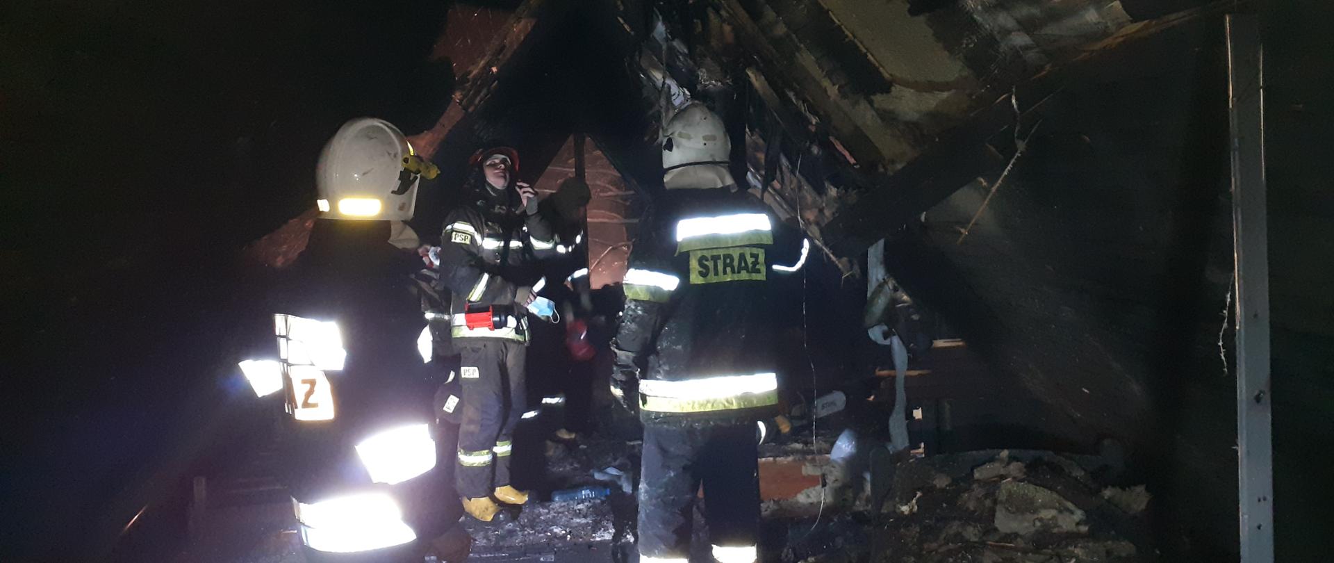 Na zdjęciu strażacy PSP i OSP oglądają zniszczone poddasze po pożarze