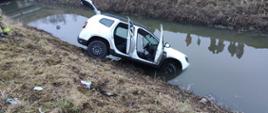 Na zdjęciu widoczny biały samochód - Ducia Duster częściowo w cieku wodnych. Zanurzony częściowo przód pojazdu.