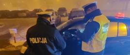 Od lewej: umundurowany funkcjonariusz Policji i Inspekcji Transportu Drogowego stoją obok kontrolowanego pojazdu, którym jest wykonywany zarobkowy przewóz „na aplikację”. (Fot. KMP Białystok)