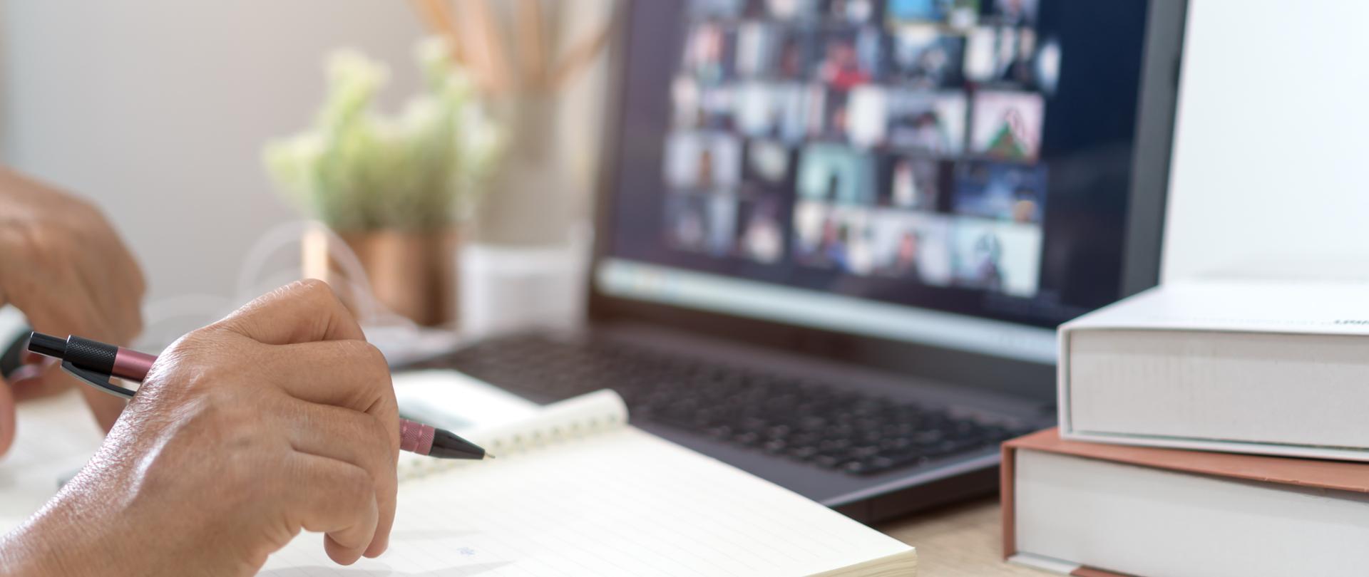 Spotkanie online za pośrednictwem laptopa. na pierwszym planie ręce i notatnik