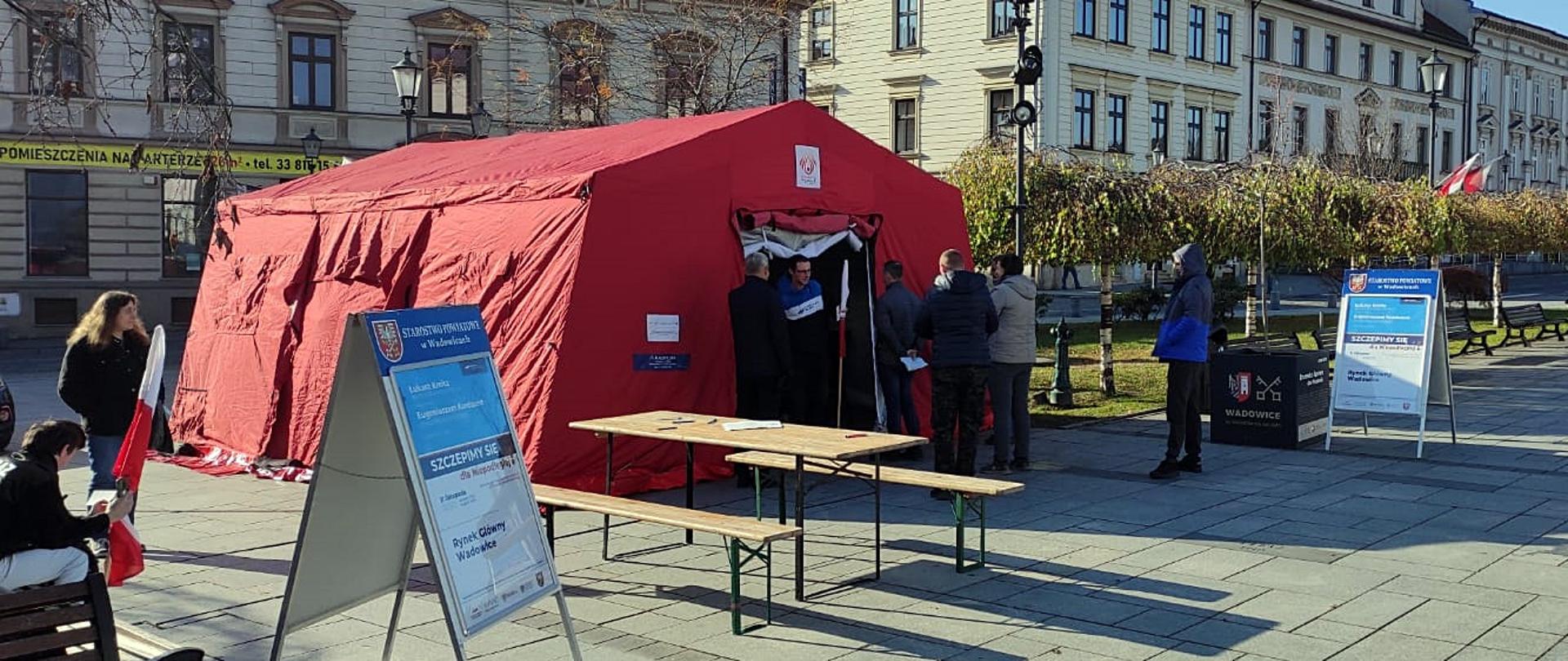 Widok z boku. Na Placu Jana Pawła II w Wadowicach widoczny rozstawiony namiot OSP w kolorze czerwonym. W tle kamienice. 