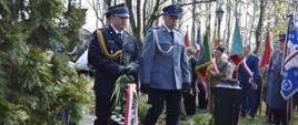 Na zdjęciu zastępca komendanta KP PSP Śrem wraz z funkcjonariuszem policji podczas składania wiązanki kwiatów pod pomnikiem z boku stoją poczty sztandarowe