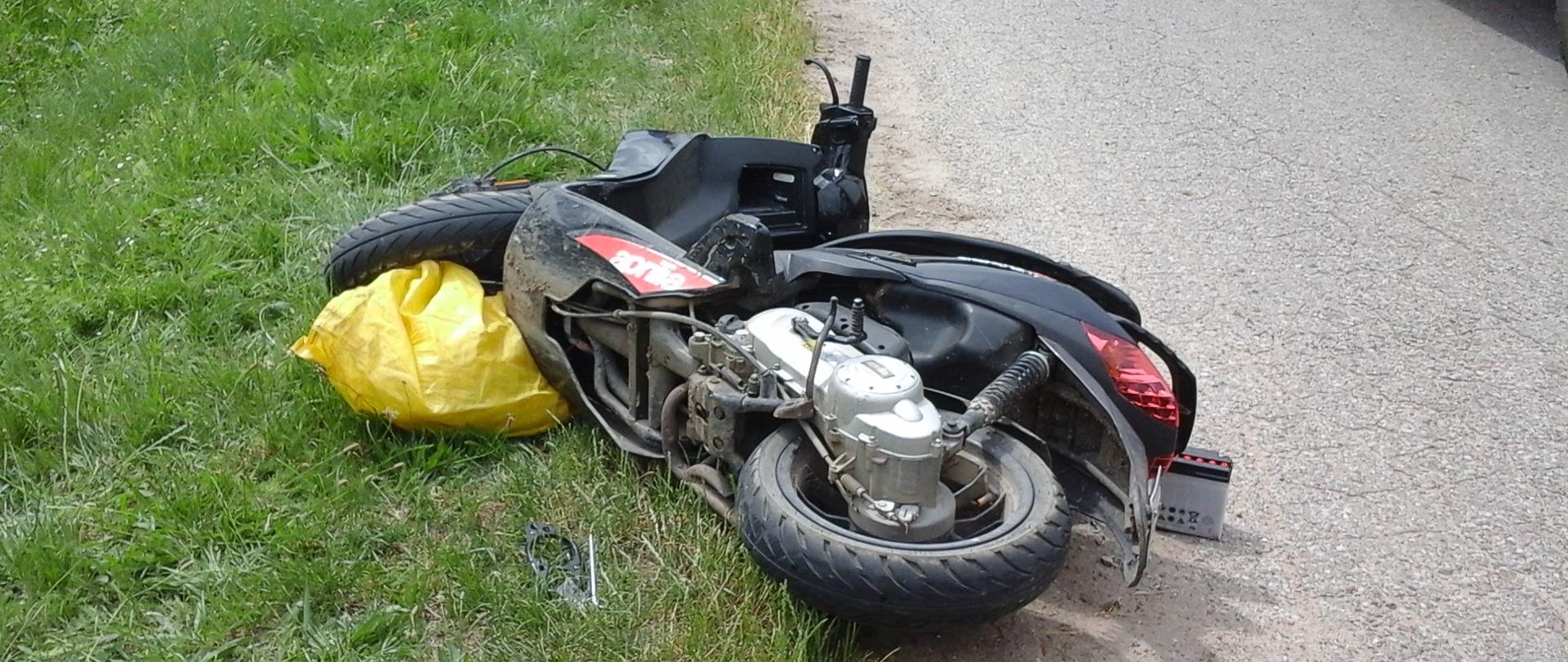 Motocykl leżący na jezdni po zderzeniu z samochodem osobowym