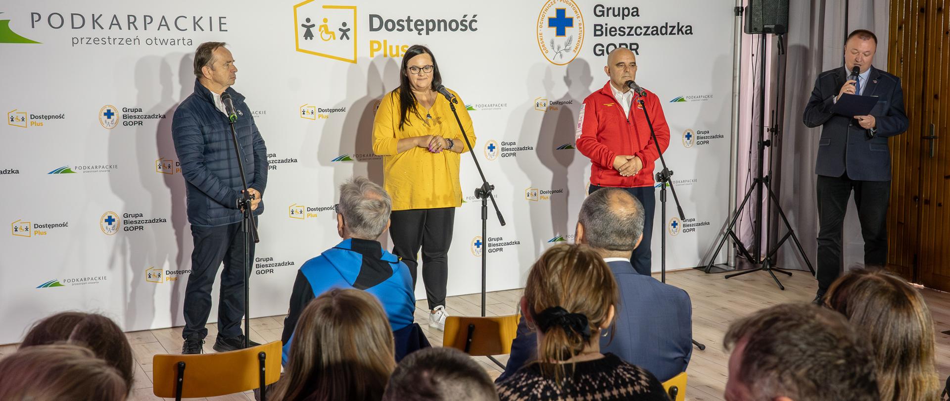 Cztery osoby stoją przed mikrofonami. Druga od lewej wiceminister Małgorzata Jarosińska-Jedynak. Na krzesłach siedzi publiczność