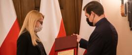 Wojewoda łódzki Tobiasz Bocheński wręczający symboliczną tabliczkę wyróżniającej się operatorce numeru alarmowego łódzkiego CPR
