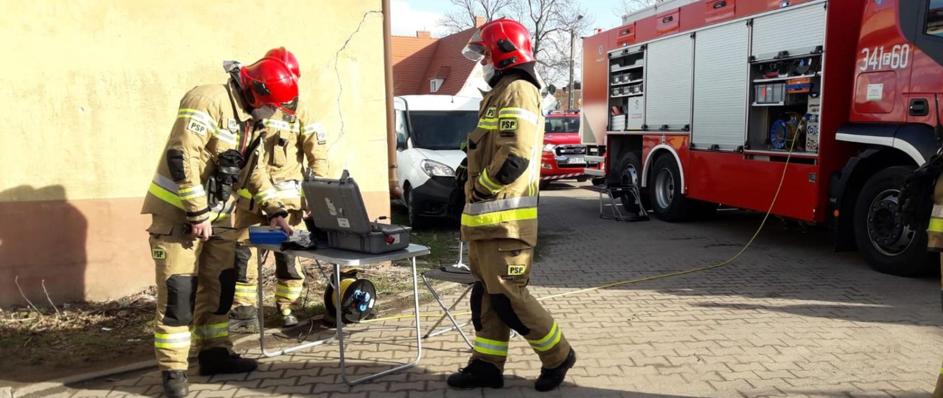 Na zdjęciu znajduje się samochód specjalny grupy ratownictwa chemicznego z Zielonej Góry i strażaków, którzy wykonują czynności pomiarowe substancji.