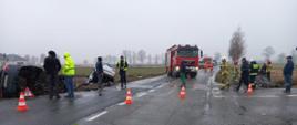 Samochody po wypadku znajdują się rowie. Na drodze samochód strażacki.