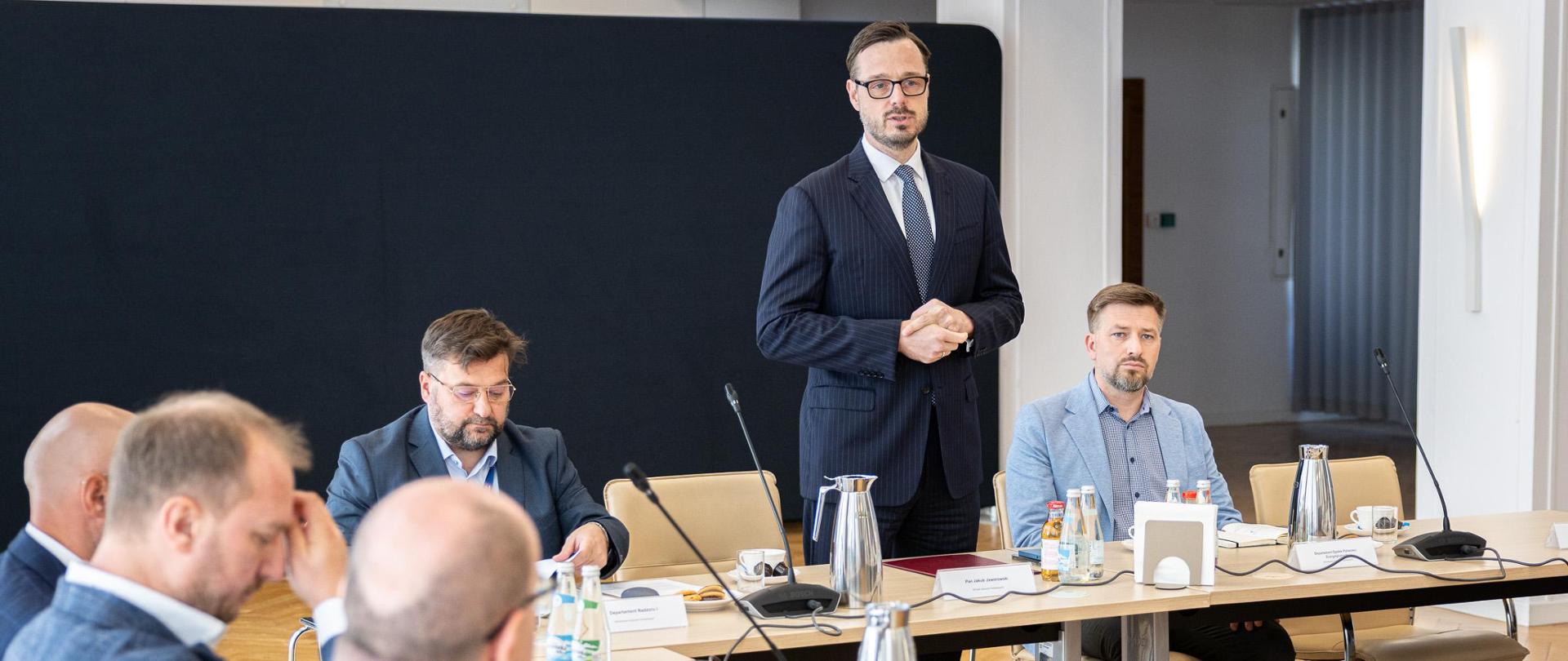 Minister Jakub Jaworowski i inni mężczyźni siedzą wokół okrągłego stołu.
