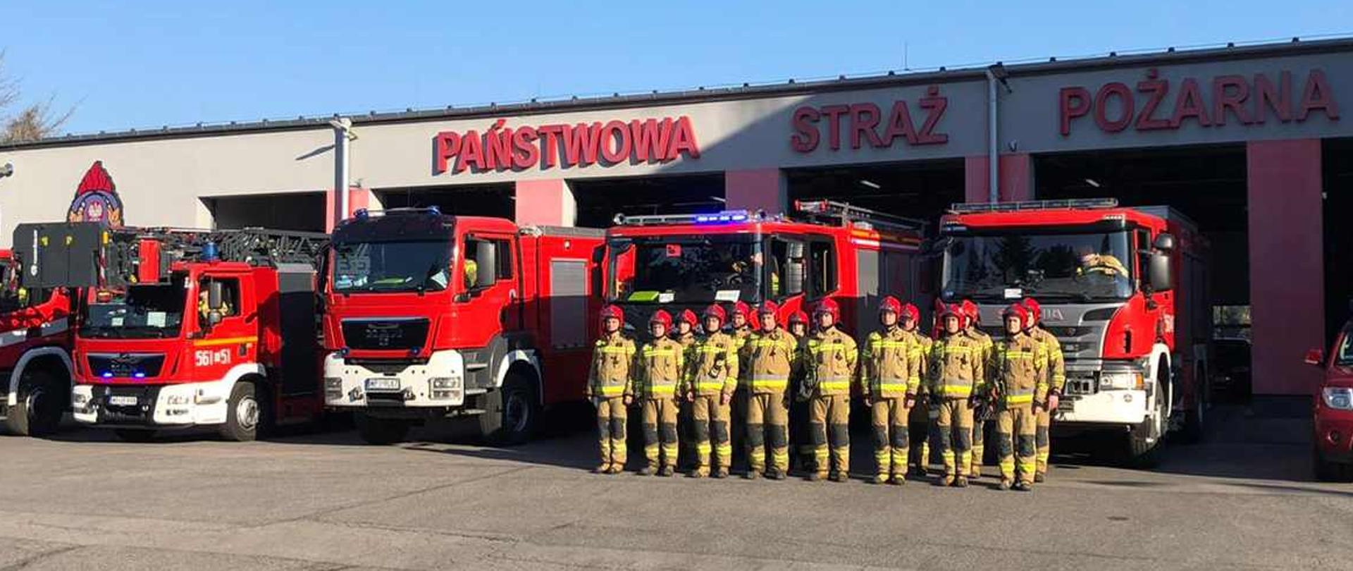 Przed garaże wyjechało 6 samochodów przed nimi stoją umundurowani strażacy z JRG Piaseczno