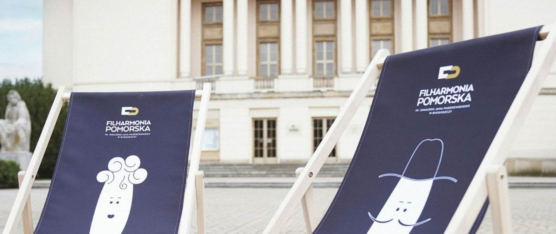 na tle budynku Filharmonii Pomorskiej dwa niebieskie leżaki
