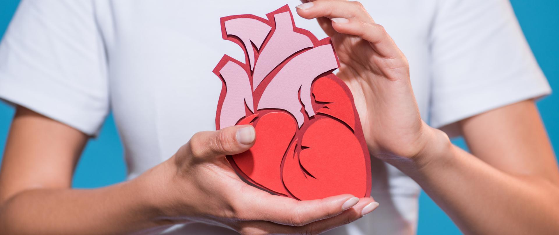 Na zdjęciu jest kobieta trzymająca papierowe serce w dłoniach.