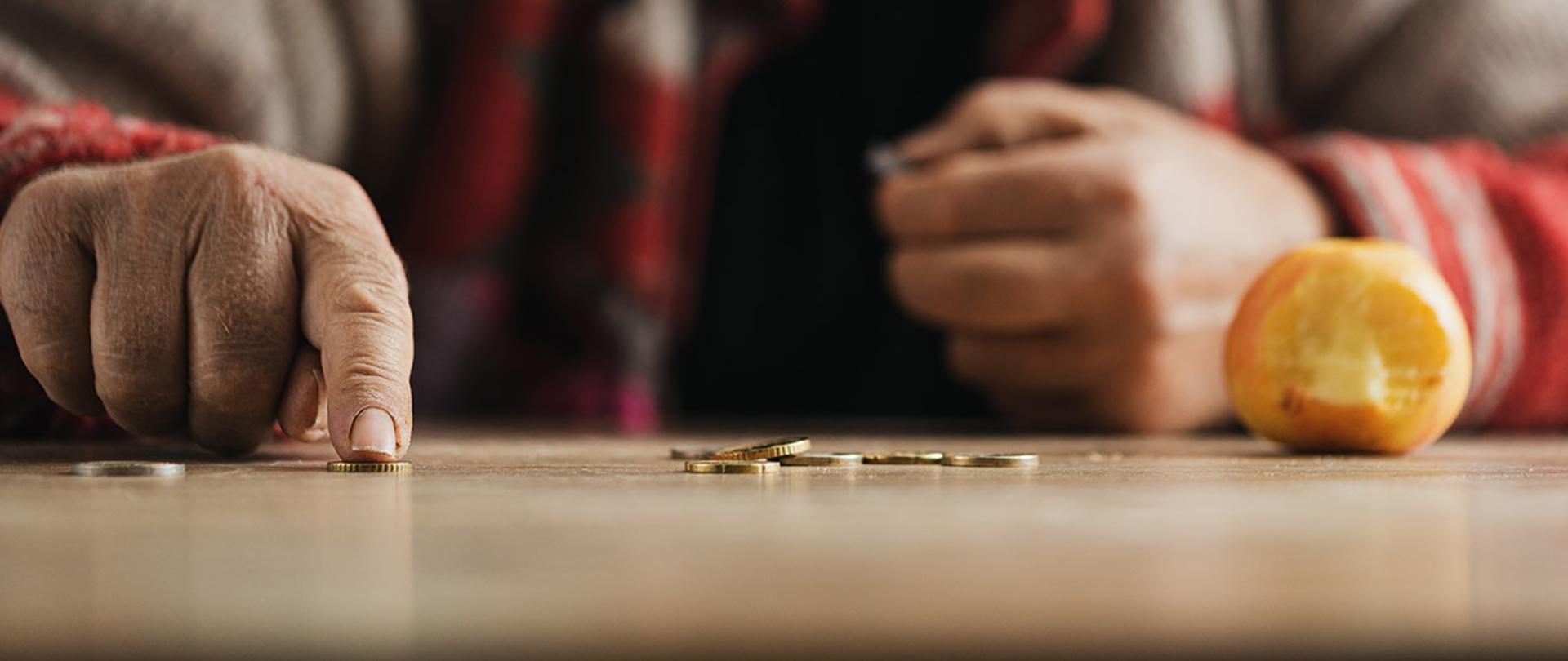 Dłonie starszej kobiety, kobieta liczy monety. 