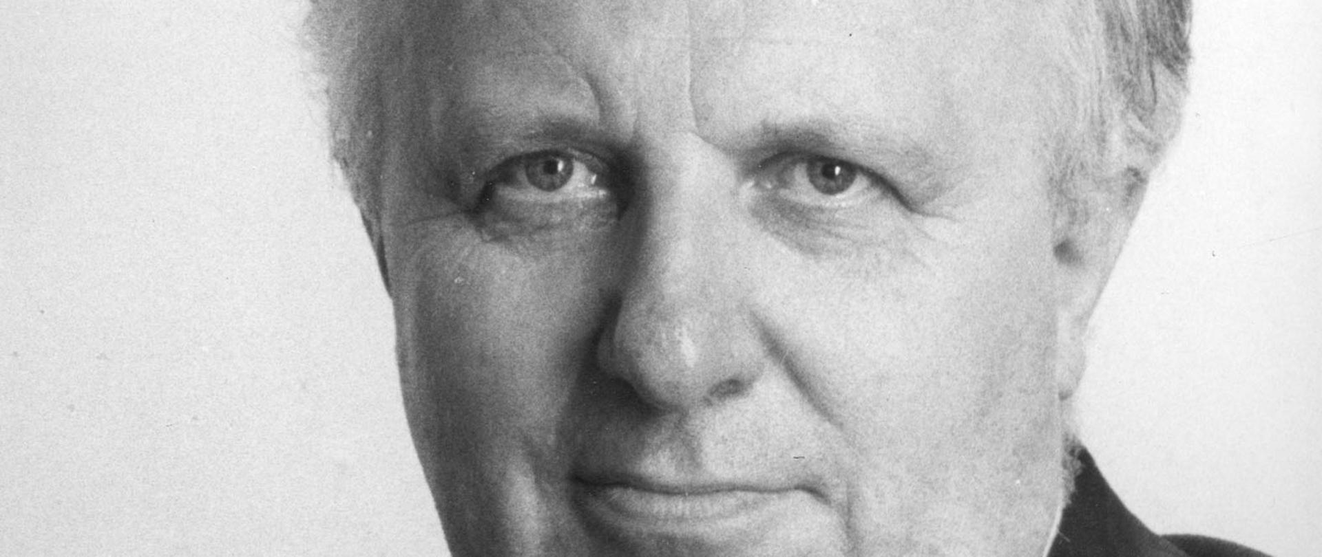 Stefan Olszowski - czarno - biały portret mężczyzny, siwiejące włosy, ciemna marynarka, ciemny krawat, biała koszula.