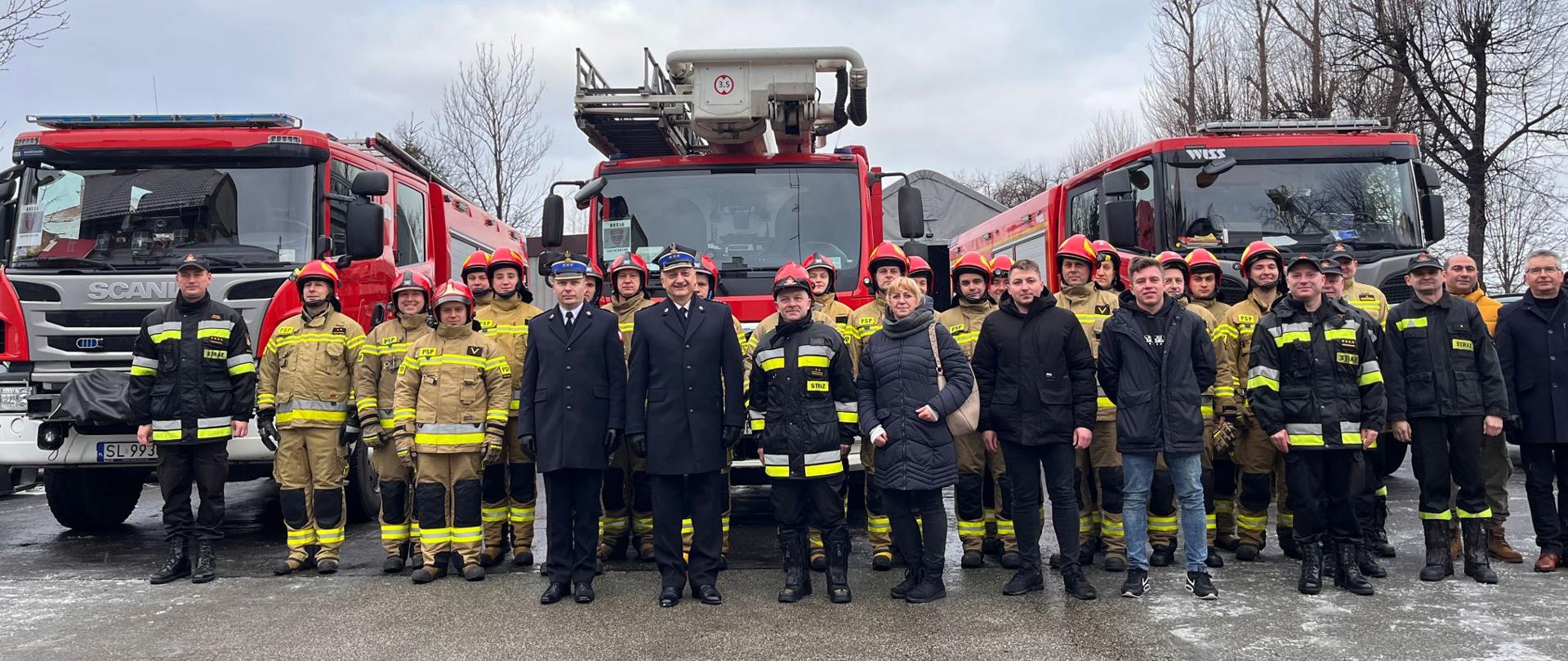 Zdjęcie przedstawia pamiątkową fotografię odchodzącego na emeryturę D-cę JRG nr 2 w Rudzie Śląskiej bryg. Piotra Adamusa z kadrą KM PSP Ruda Śląska, funkcjonariuszami podziału bojowego, emerytami oraz najbliższą rodziną.