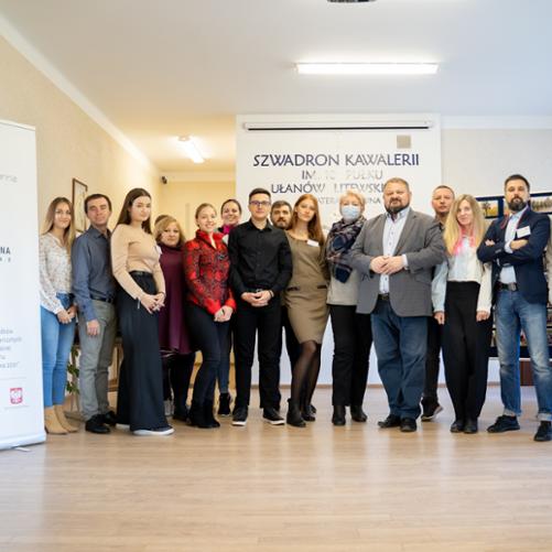 Grupa ludzi pozuje przy rolapach z logiem Polska-Ukraina Sąsiedztwo.