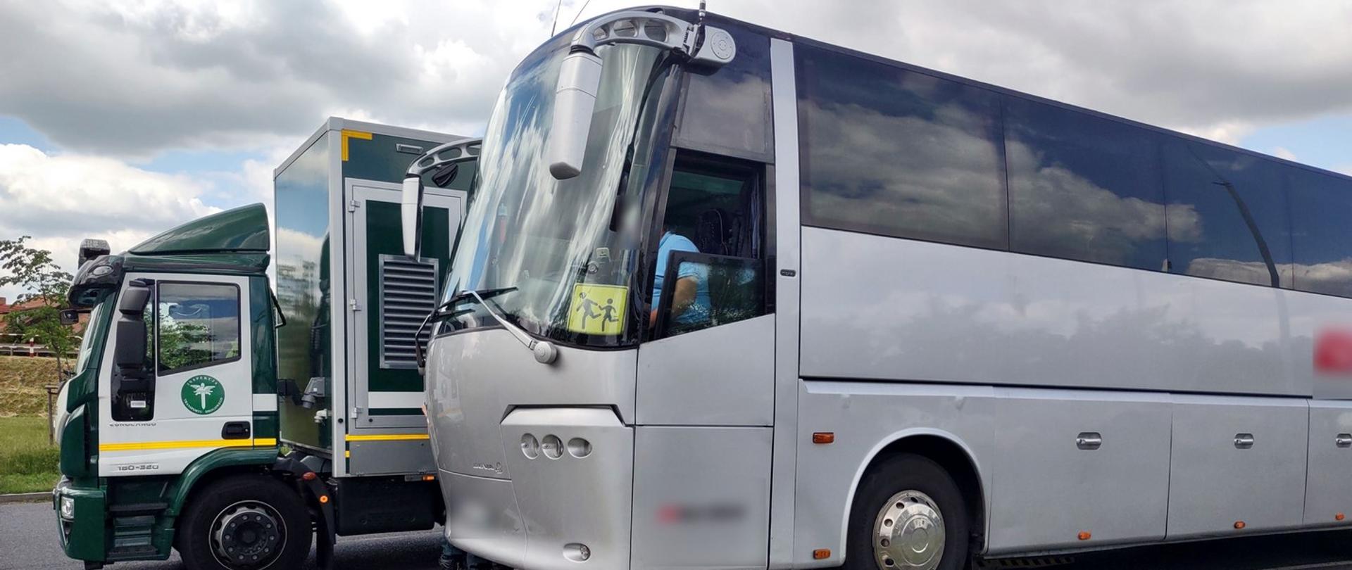 Szary autobus stojący na rampie diagnostycznej. Za nim zielony pojazd Mobilnej Jednostki Diagnostycznej