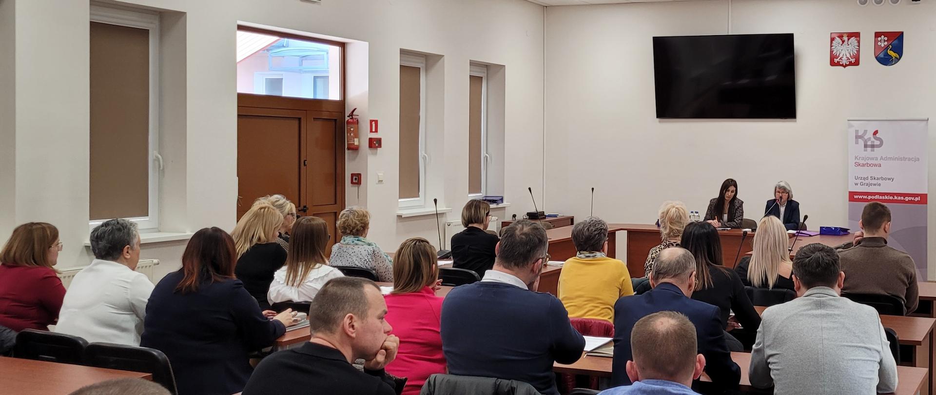 Spotkanie informacyjne dot. zmian podatkowych prowadzone przez przedstawicieli US w Grajewie, ludzie siedzący w ławkach