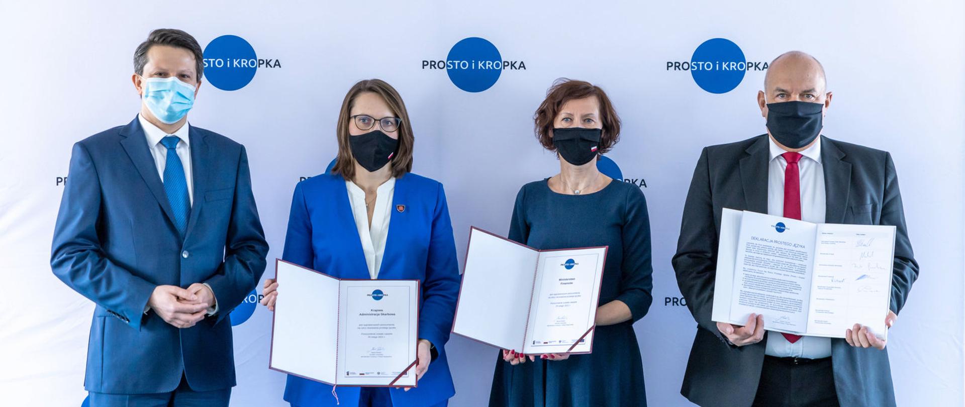 Cztery osoby na zdjęciu, trzy trzymają podpisane deklaracje. Od prawej: minister finansów, funduszy i polityki regionalnej Tadeusz Kościński, dyrektor generalna Ministerstwa Finansów Renata Oszast, szefowa KAS Magdalena Rzeczkowska, dyrektor generalny Ministerstwa Funduszy i Polityki Regionalnej Marek Redźko.
