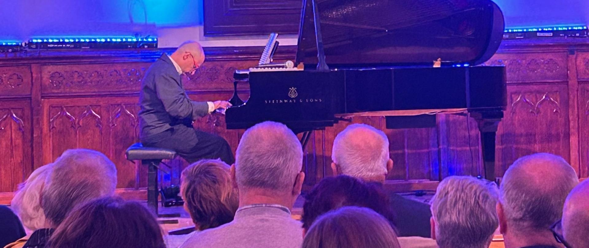 Pianista Manuel Fernandez występuje przed publicznością w Sali Królewskiej, grając muzykę filmową na fortepianie.