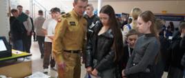  Stoisko KP PSP w Rawiczu Strażak przekazuje odwiedzajcym wiedzę na temat możliwości wstąpienia do służby. Na stole leżą informatory. 