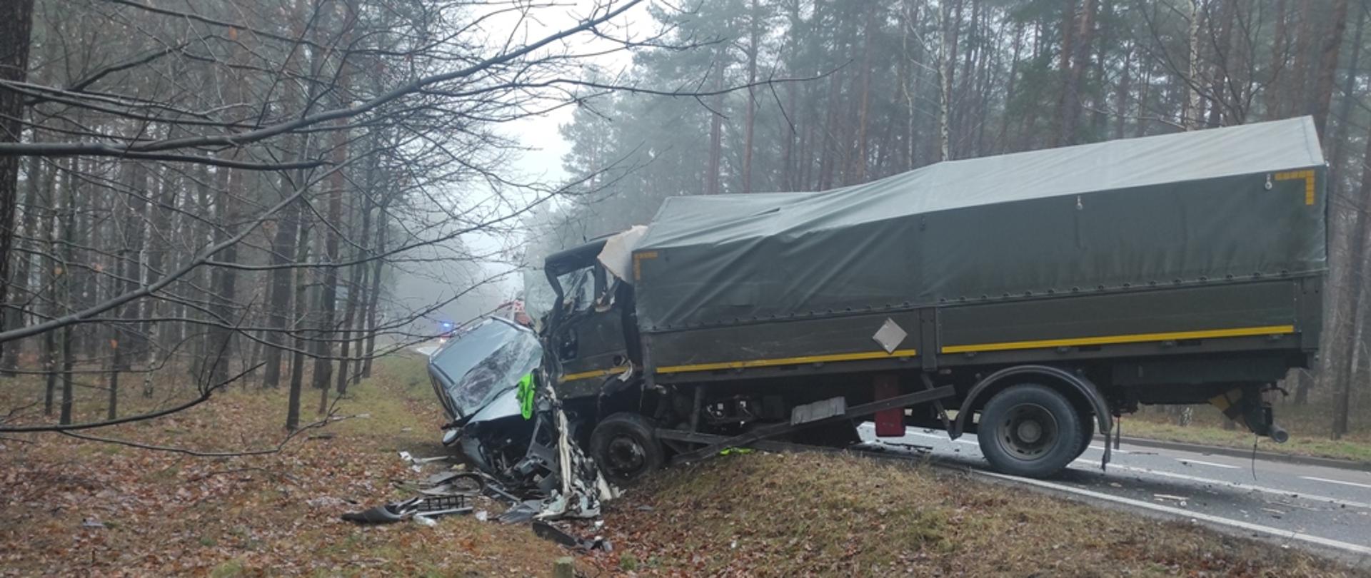 Ciężarówka wojskowa i samochód osobowy stoją w rowie.