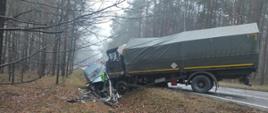 Rozbita ciężarówka wojskowa i samochód osobowy stoją w rowie