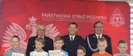 Eliminacje powiatowe OTWP. Świetlica Komendy Powiatowej PSP w Rawiczu. Na tle ścianki PSP stoi 6 uczestników turnieju z grupy I, którzy trzymają w rękach otrzymane wcześniej dyplomy i nagrody. Za nimi trzech strażaków PSP i OSP w mundurach galowych.