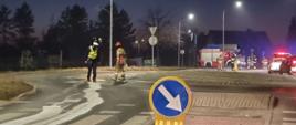 Strażacy z miotłami usuwają plamę oleju z drogi.