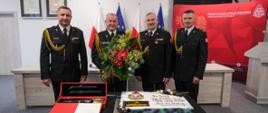 Kierownictwo KP PSP w Gdańsku. Po środku stoi nadbryg. Jacek Niewęgłowski z kwiatami. Przed komendantami atrybuty generalski oraz tort.